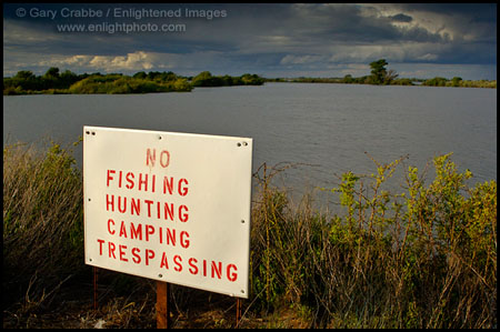Warning sign and thunderstorm clouds over Sacramento River, near Rio Vista, Solano County, California