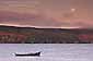 Full moon setting at sunrise over a lone dory in Tomales Bay, Marin County, California