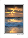 Sunset through coastal fog over ocean waves breaking on Torrey Pines State Beach, San Diego County Coast, California