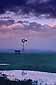 Windmill in pasture lands at sunset beneath spring storm clouds, Central Valley, California