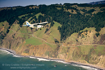 Small single-engine plane flying over the California coastal cliffs, Sonoma County, California