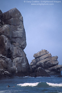 Surfer below rocks at the base of Morro Rock, Morro Bay, California; Stock Photo photography picture image photograph fine art decor print wall mural gallery