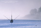 Commercial fishing boat in fog on calm blue water, San Simeon Bay, Central Coast, California