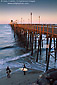 Two young boy surfers checking out the ocean waves at the base of the historic wooden Oceanside Pier, Oceanside, Northern San Diego County Coast, California