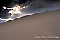 Sunbeams through dark storm clouds over sand dune, near Stovepipe Wells, Death Valley National Park, California