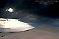 Sunlight and dark storm clouds over desert sand dune, near