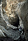 Hiker climbing rock wall into narrow Grotto Canyon, Death Valley National Park, California