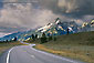Twisting curve on road beneath storm clouds and mountains, Grand Teton National Park, Wyoming
