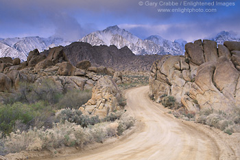 Photo: Dirt road below snow covered mountain peaks during a spring storm, Eastern Sierra, California